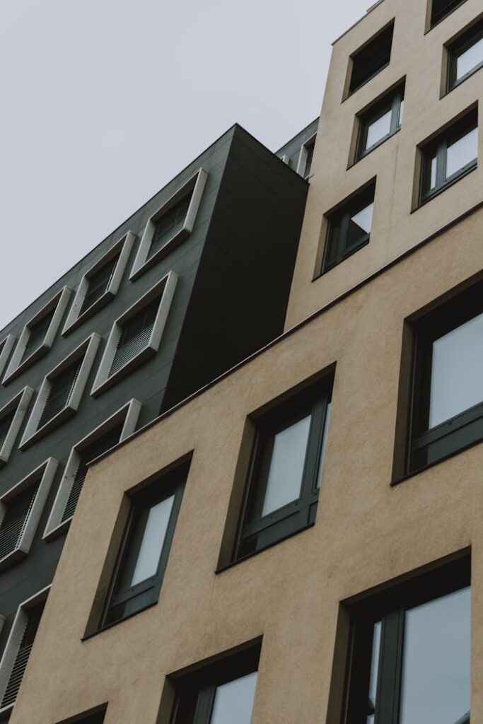 From below contemporary building with brown and black facade and windows against gray sky at daytime